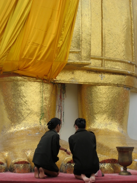 Women praying at the foot (literally) of a very tall Buddha